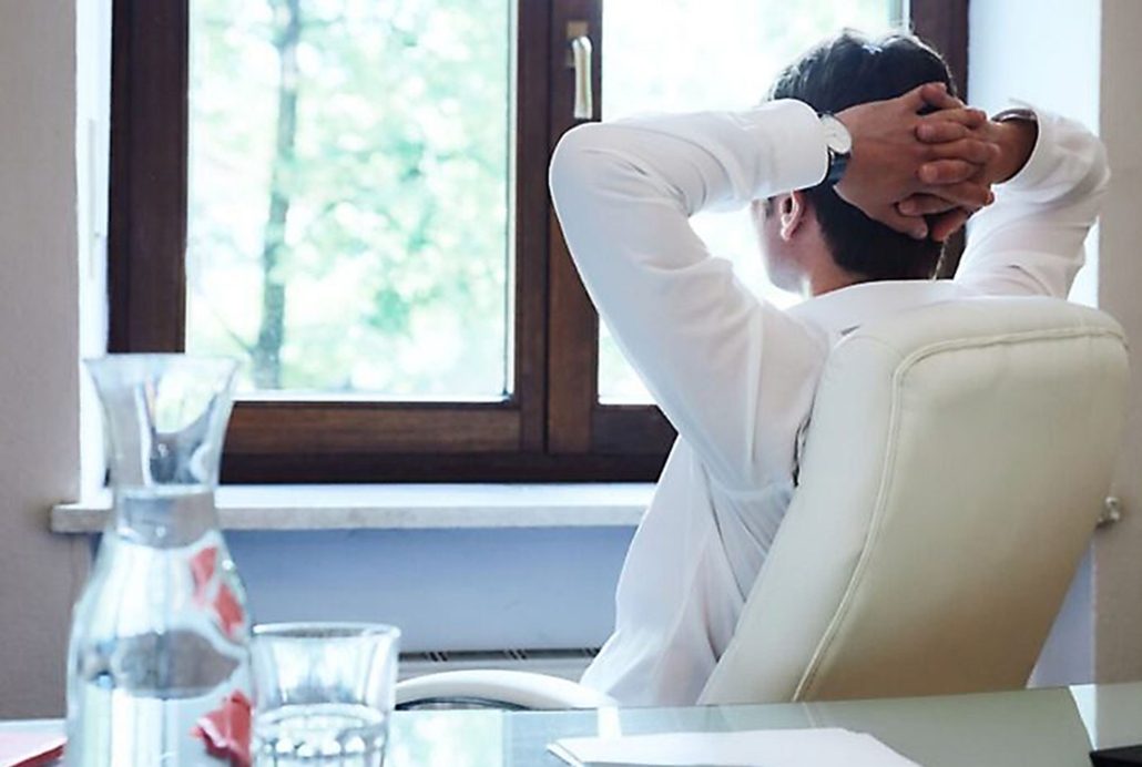 Executive Coaching München: Ein Mann im weißen Hemd lehnt sich zurück und blickt aus dem Fenster ins Grüne